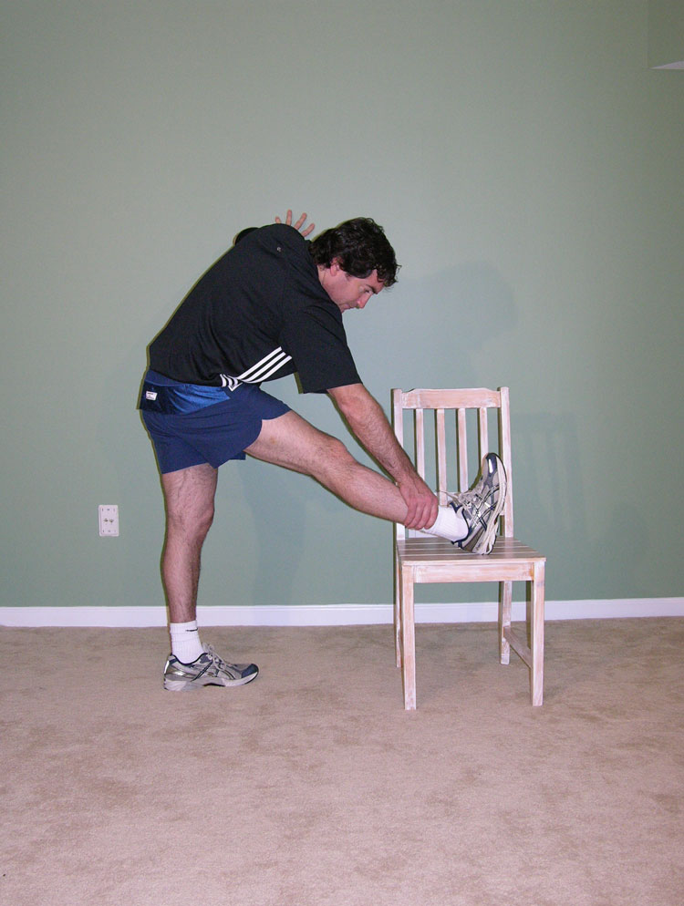 Man leaning over, stretching leg on chair